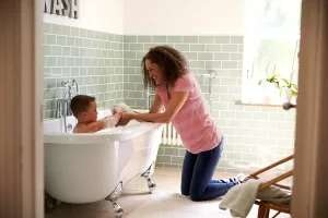 nounou à domicile qui donne le bain à un enfant